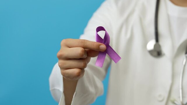 Young male doctor shows a purple ribbon, symbol of the fight against testicular cancer, lupus, Alzheimer's, domestic violence, woman abuse, feminism - Powered by Adobe