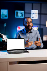 BIPOC influencer holding isolated screen laptop in his hands, talking about specifications to social media followers audience. Online show host presenting mockup notebook features