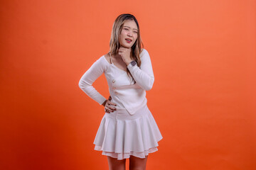 gesture young beautiful indonesia woman white top standing candid close eyes pain sore throat hands hold waist and neck isolation orange background. for health, advertising, science, commercial