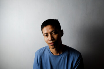 portrait of asian man in blue shirt looking at camera. white background