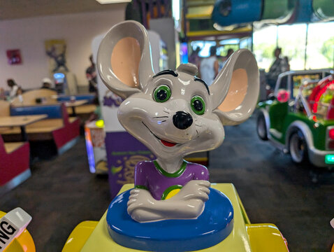 Chuck E. Cheese animatronic character smiling at children in an entertainment center during a busy afternoon