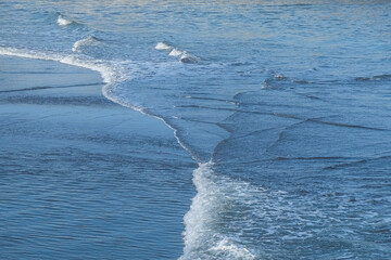 Abstract shapes, patterns and textures of sea waves on the sand. The meeting of the reverse current...