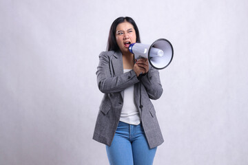 beautiful female screaming formal angry candid both hands holding loudspeaker megaphone forward wearing gray suit isolated on white background. fashion, lifestyle, advertising, sale, company concept