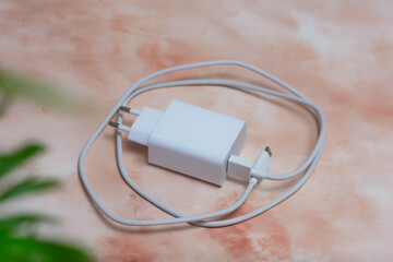 White USB smartphone charging cable and power adapter on a marble table.