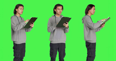 Asian guy reads information on files, thinking about annotations on clipboard papers or taking...