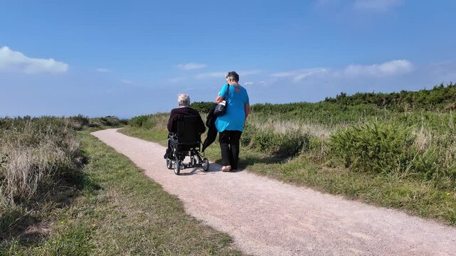 Devon England UK. 30.09.2024. Video. Elderly man using an electric wheelchair along a coastal pth in south Devon UK.