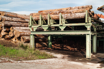 Stacked logs in sorting machinery or metal conveyor. Tall stack of lumber or timber ready to be...