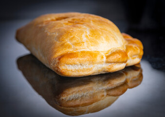Cornish pasty,close detailed view, on a black mirrored surface.