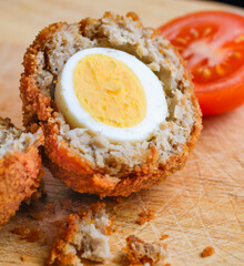 Traditional Scotch Egg,close-up and cut into two half segments,being prepared on a domestic kitchen wood bread board.