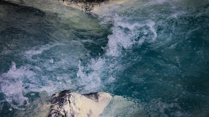 Swift river current flowing around large rocks, capturing the natural power and movement of water