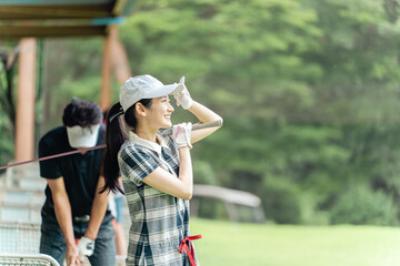 ゴルフ練習場・打ちっぱなし・ゴルフセンターでスイングの練習するゴルフ選手・ゴルファーの女性
