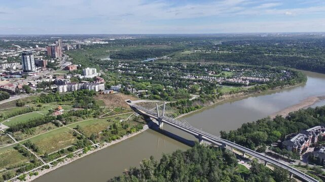 Edmonton, AB, Canada, aerial video footage starting at Tawatin&acirc; LRT Bridge crossing North Saskatchewan River with left panning across Edmonton Downtown skyline with old and modern buildings