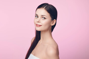 Naklejka premium Beautiful young woman with long straight hair posing on a pink background