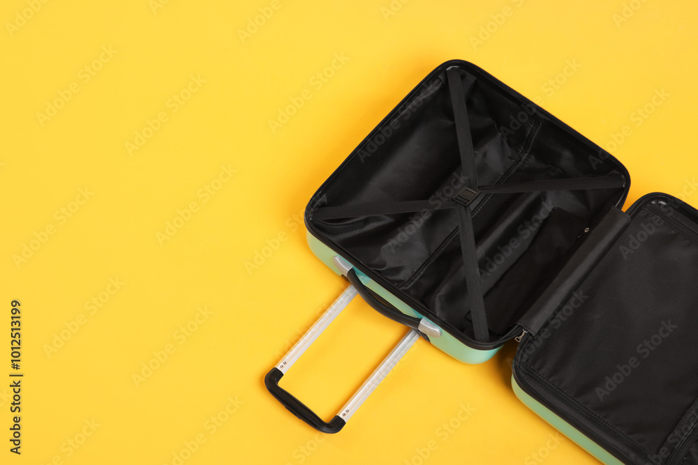 Wall mural Open empty suitcase on yellow background, above view. Space for text