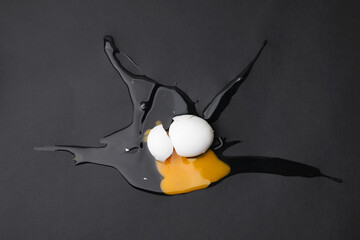 One raw broken egg on black background