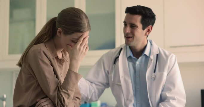 Empathetic male gynecologist doctor in coat comforting young woman patient try to calm down after bad news about terminating pregnancy for medical reason or infertility, give her psychological support