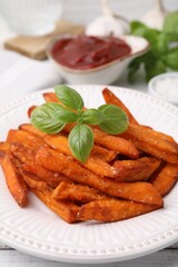 Sweet potato fries and basil on table, closeup