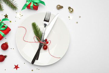 Christmas table setting with plate, cutlery and festive decor on white background, flat lay. Space for text