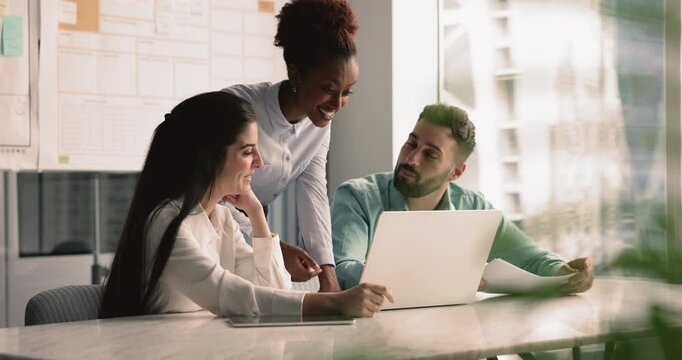 Three colleagues use laptop, sharing information, insights or updates relevant to discussion, working on report or presentation, review joint online task, engaged in new software learning at workplace