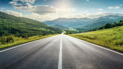A straight asphalt road through green mountain landscapes, under a sunny sky with gentle white clouds.