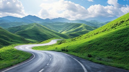 Fototapeta premium A winding asphalt road cutting through vibrant green mountains, with a bright sky and a few scattered clouds.