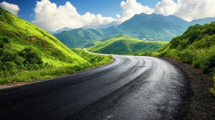Naklejka premium An asphalt road winding through lush green mountains, with a bright sky and fluffy clouds on a clear, sunny day.