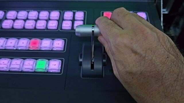 Close up of man's hand working with console bar of video switcher. Video mixer in broadcast television production studio.