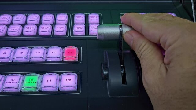 Close up of man's hand working with console bar of video switcher. Video mixer in broadcast television production studio.