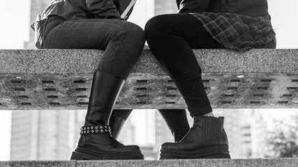 Artistic black and white close-up of a couple of women's legs resting on a bench