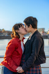 Fototapeta premium Young lesbian couple lovingly entwined, sharing a kiss while holding hands