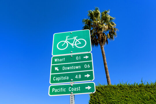 Green bicycle route sign points to local destinations in Santa Cruz, California, including the Wharf, Downtown, UCSC, and the Pacific Coast