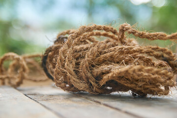 coconut coir fiber rope on table top in close-up view, natural eco friendly waterproof brown strings in selective focus in blurry outdoor background with copy space