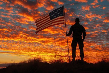 Silhouette of a soldier holding the American flag against a vibrant sunset.