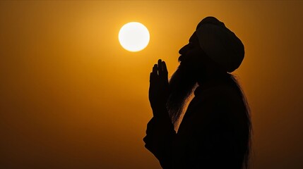 A man in a turban is silhouetted against the setting sun