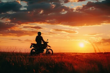 motorcyclist and enduro motorcycle silhouette at sunset in field