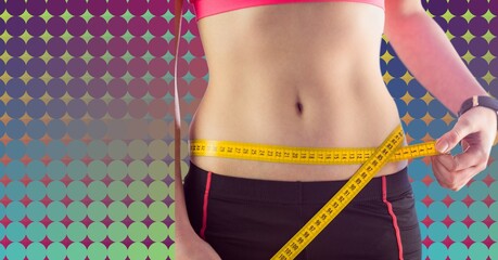Mid section of caucasian fit woman measuring her waist against colorful background with copy space