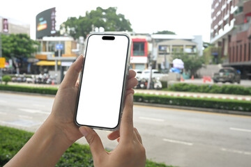 Hands holding mobile phone with a white screen on blurred background of a city street