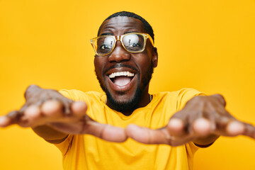 Happy young man showing excitement in yellow shirt and glasses against a bright yellow background, conveying joy and positivity in a vibrant, energetic atmosphere