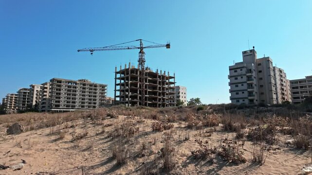 Abandoned buildings with construction crane in Varosha under clear blue sky