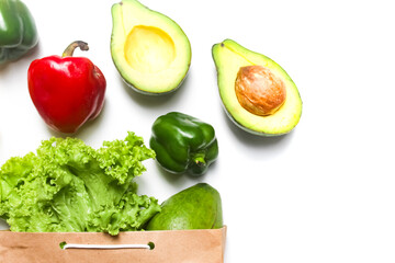 close up of concept of fresh vegetables coming out of a paper bag, on white background