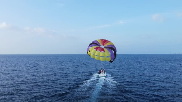 Motorboat Launching Parasailing Couple into The Sky Over Blue Ocean, Drone Back View