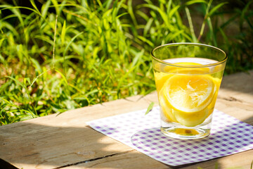 a glass of water lemon with grass background    