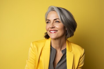 Portrait of happy senior businesswoman looking at camera over yellow background - Powered by Adobe