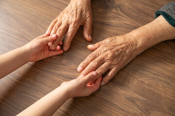 Elderly female and child hands together.