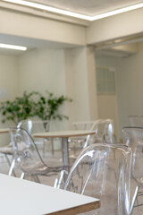 Seating inside the cafe or restaurant, with transparent chairs and white tables.