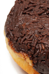 A whole donut without a hole, topped with hardened chocolate glaze and generously covered in chocolate sprinkles. Photographed on a white background.
