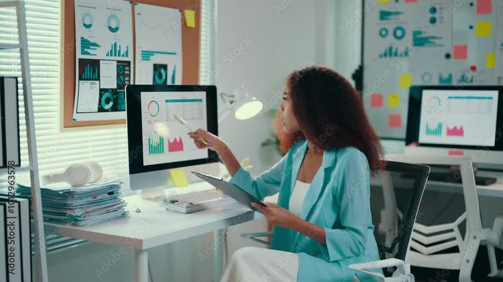 Poster african american businesswoman works in an office, analyzing financial graphs on a computer while ta
