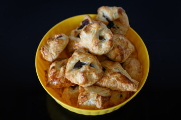 Close-up of scarf puff pastry with jam in a yellow bowl.
