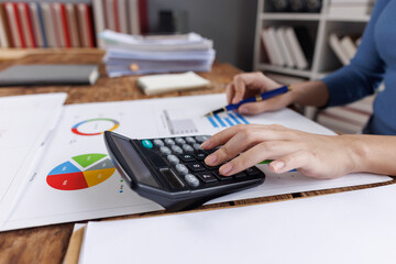 Business financing accounting banking concept. Business woman hand doing finances and calculate on desk about cost at home office. Woman working on desk with using calculator, finance accounting.
