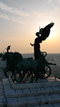 Vista aerea dell'angelo con i cavalli in cima all'altare della Patria nel centro della citt&agrave; di Roma. Il sole in controluce passa attraverso le ali.